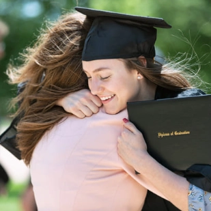 Une jeune femme venant d'être diplômée prend sa mère dans les bras