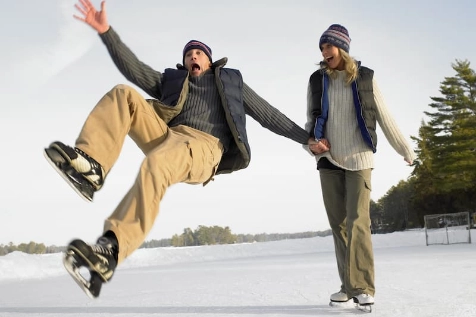 Un couple fait du patin à glace, l'homme est en train de glisser et va tomber