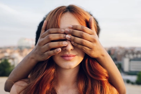 Une femme a les yeux cachés par par les mains d'une seconde personne