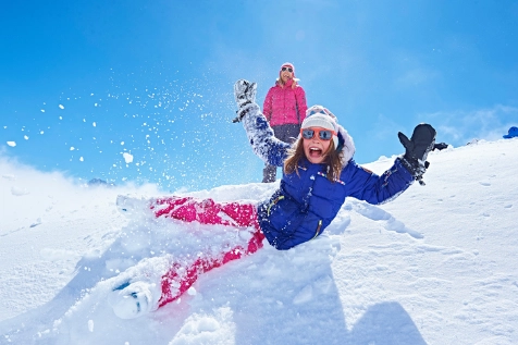 Jeune fille qui se laisse tomber dans la neige. Vacances au ski. 
