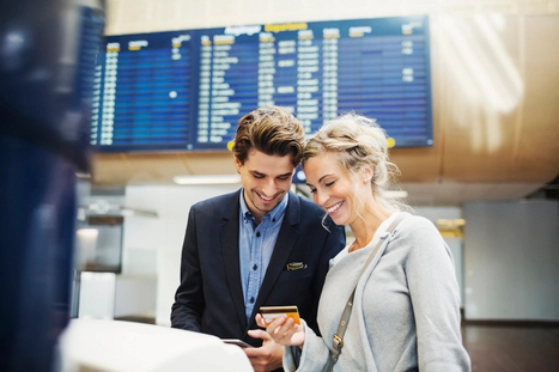 Un couple utilise une carte bancaire pour payer dans un aéroport à l'étranger