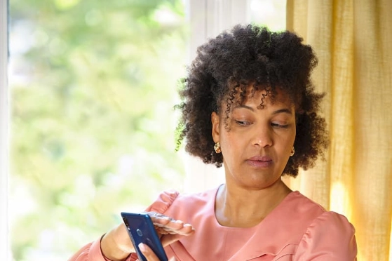 Une femme regarde son smartphone de côté et couvre l'écran avec sa main