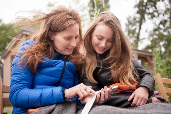 Une mère et sa fille adolescente discutent en regardant le smartphone de la mère