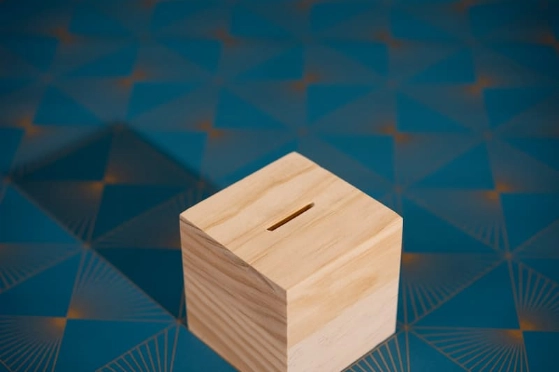 Une tirelire en forme de cube en bois sur fond bleu