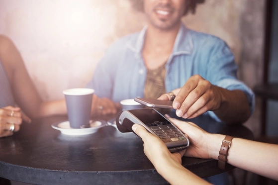 Groupe d'amis dans un café utilisent leur mobile pour payer avec Google Pay et Apple Pay