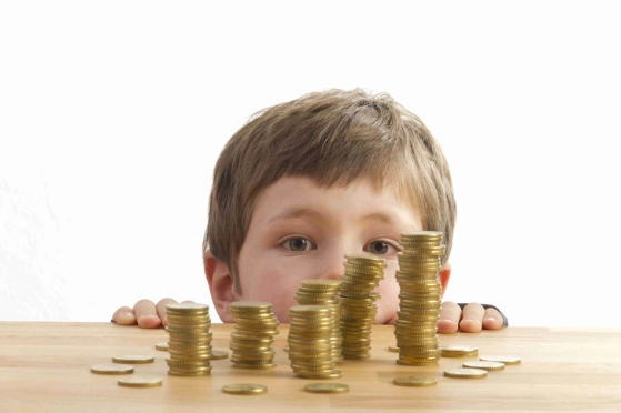 petit garçon regarde des piles de pièces sur une table