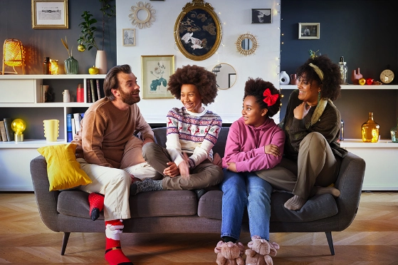 Famille souriante assise sur une canapé dans leur salon.  