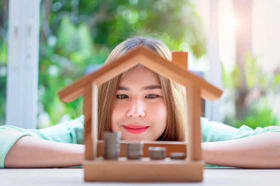 Une femme regarde des piles de pièces de monnaie, disposées dans une petite maison en bois.