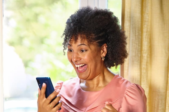 Une femme sourit en découvrant les avantages fidélité de sa carte bancaire Orange Bank