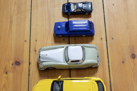 De petites voitures jouets sont disposées par ordre de taille sur le sol