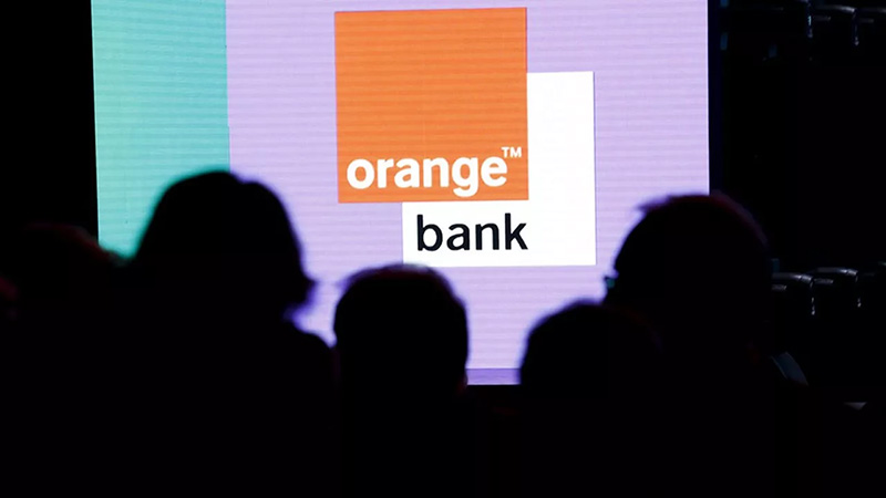 Foule à contre-jour regardant le logo Orange Bank.   