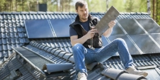 Un homme installe des panneaux solaires sur le toit d'une maison